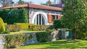 A stone building with a red-tiled roof, a large arched window, and a green door. - Beautiful Villa with Private Pool and Garden (Massa Lubrense)