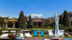 A swimming pool with lounge chairs and a ladder, surrounded by greenery and buildings in the background. - Beautiful Villa with Private Pool and Garden (Massa Lubrense)