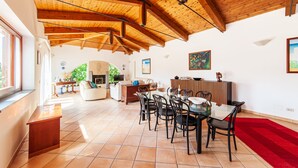 A spacious living area with a high wooden ceiling, a dining table with chairs, and a red carpet. - Beautiful Villa with Private Pool and Garden (Massa Lubrense)