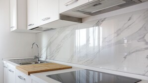 Une cuisine moderne avec un dosseret en marbre, une cuisinière encastrée et un évier en acier inoxydable.