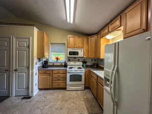 Une cuisine avec des meubles en bois, un four blanc, un four à micro-ondes et un réfrigérateur.