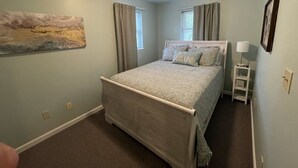 A bedroom with a bed, a nightstand, a lamp, and a painting on the wall.