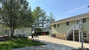 A residential area with a paved driveway, a stone retaining wall, and a two-story house with a balcony.