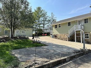Zona residencial con camino de entrada pavimentado, muro de contención de piedra y una casa de dos pisos con balcón.