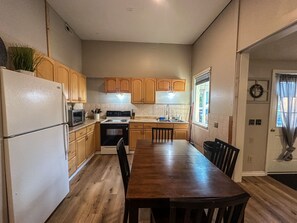 A kitchen with wooden cabinets, a refrigerator, stove, and a dining table with chairs. - Lake Retreat on 20 acres with Hot Tub near Athens (Albany)