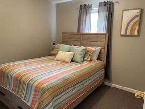 Een slaapkamer met een bed, gordijnen en een wandlamp.