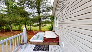 A wooden deck with a hot tub and a metal bucket.
