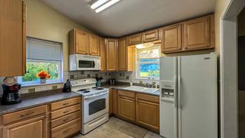 A kitchen with wooden cabinets, a white stove, a microwave, and a refrigerator.