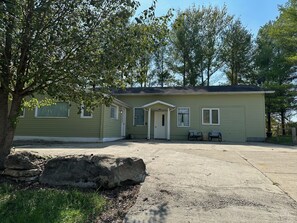 A single-story house with a front porch, two windows on the side, and a garage door.