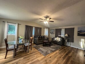 A living room with a glass dining table, two sofas, a ceiling fan, and a view of the outdoors. - Lake Retreat on 20 acres with Hot Tub near Athens (Albany)