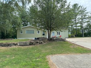 A single-story mobile home with a front porch, a small yard, and a paved driveway. - Lake Retreat on 20 acres with Hot Tub near Athens (Albany)