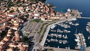 An aerial view of a coastal town with a marina, residential buildings, and a prominent church.