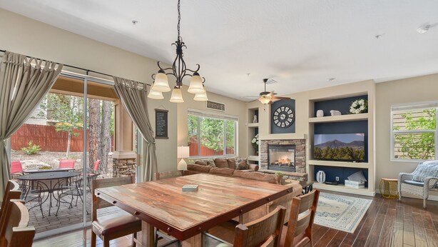 A spacious living area with a large wooden dining table, comfortable seating, a fireplace, and a large wall clock. - Beautiful & Spacious Westside Townhouse, Sleeps 8  w/ A/C.  (Flagstaff)