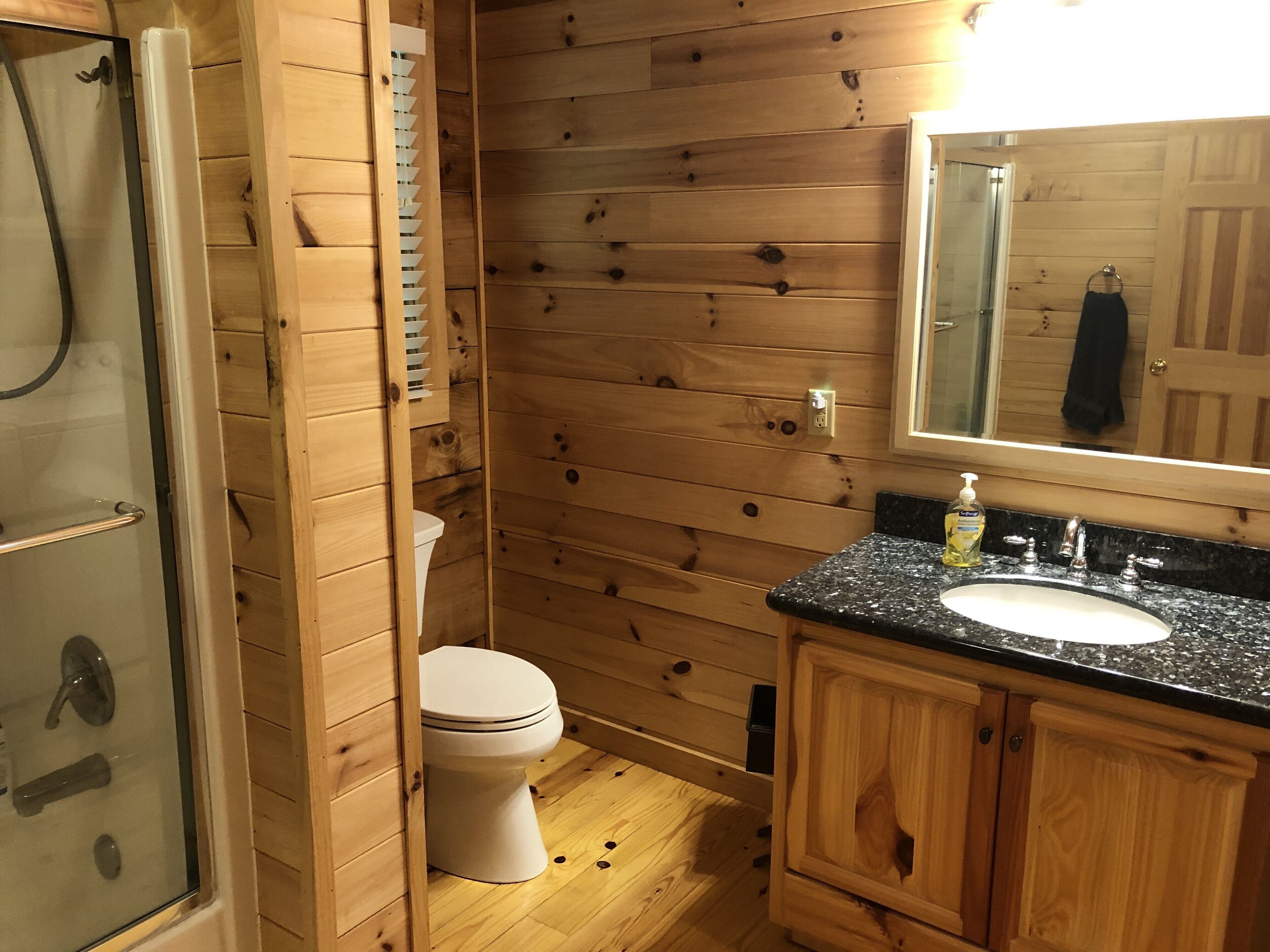 Een houten badkamer in een chalet, met een douche, toilet en wastafel.