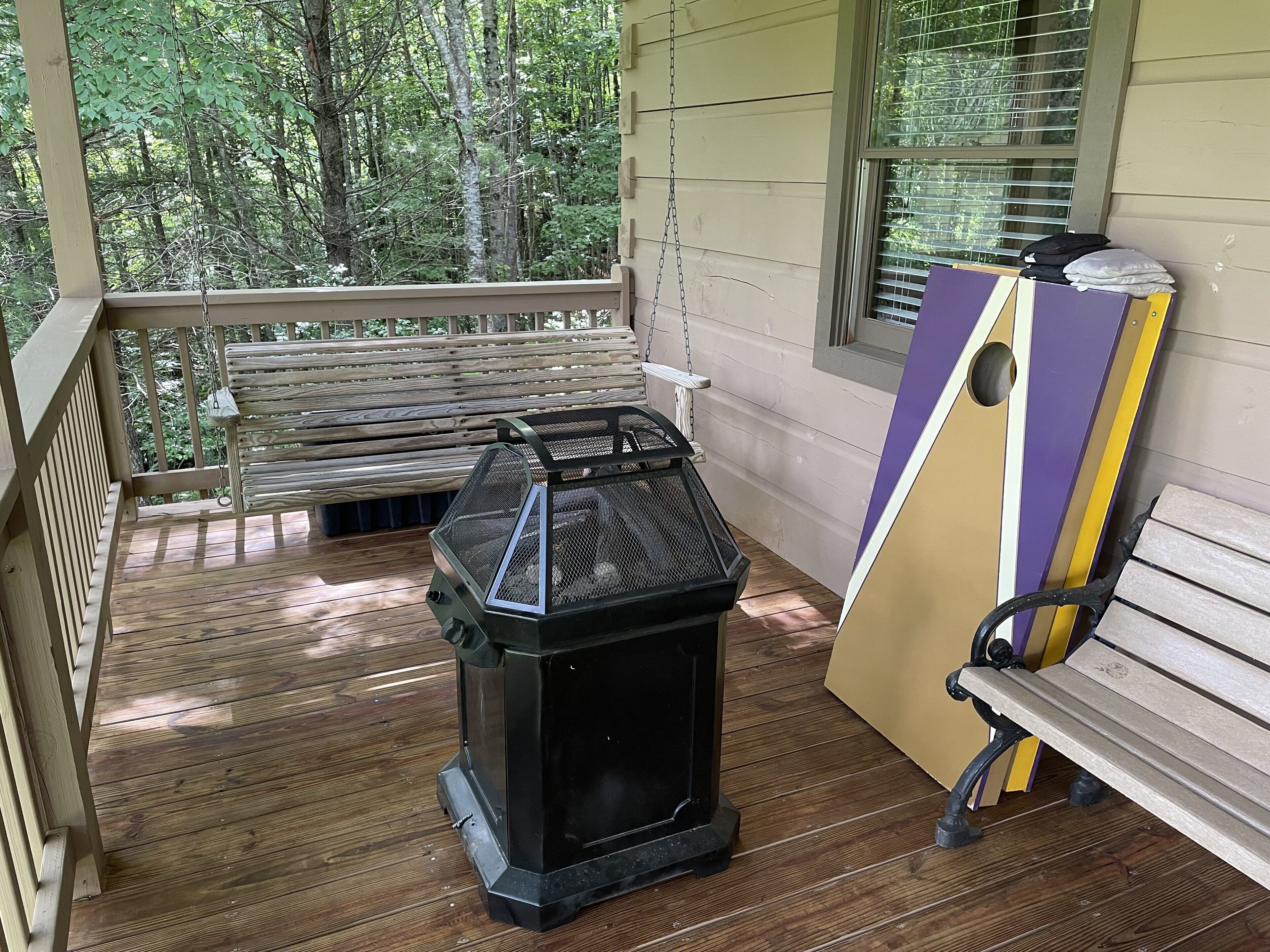 A covered porch with a grill, a bench, and a partially visible piano.