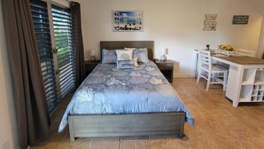A bedroom with a bed, a desk, and a chair. There is a window with curtains, a wall clock, and a framed picture. - Come Stay in Beautiful Marco Island at Marco Comfort! (Marco Island)