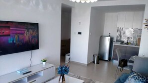A modern living room with a flat-screen TV, a white coffee table, and a blue sofa. - Astoria Apartments (Nairobi)