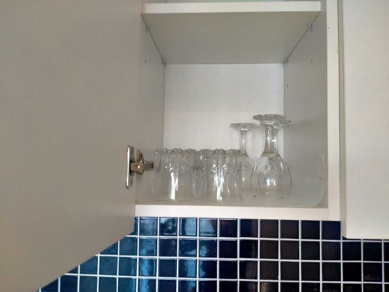 Un armario de cocina con interior blanco y salpicadero de azulejos azules.
