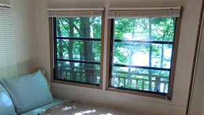 A bedroom with a bed, a window with a view of trees, and a window blind.