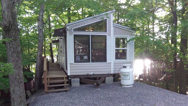 A small cabin with a porch and a propane tank nearby.