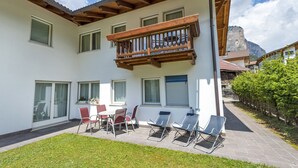 Un bâtiment à deux étages doté d’un balcon, d’un espace extérieur aménagé pour s’asseoir et offrant une vue sur la montagne.