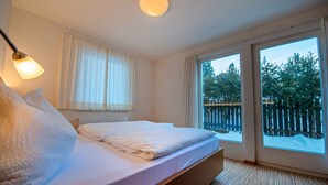 Une chambre à coucher avec un lit, une fenêtre et une vue sur les arbres à l’extérieur.