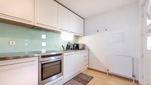 Een moderne keuken met witte kastjes, roestvrijstalen apparatuur en een glazen spatwand.