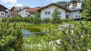 Een hotel met een siervijver, houten terras en omliggend groen.