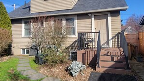 Ein zweistöckiges Haus mit Veranda, kleinem Garten und sichtbarer Klimaanlage.