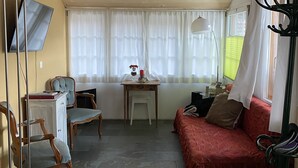 A cozy room with a wooden ceiling, a red sofa, a wooden cabinet, a small table with a vase, and a chair.