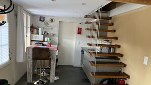 A compact kitchen with a dining area, a staircase with wooden steps, and a small living space.