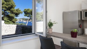 Cocina moderna con refrigerador de acero inoxidable, una planta en maceta y vista al mar a través de un ventanal grande.