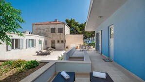 Un patio moderno al aire libre con sillones de descanso, zona de comedor y vista a un edificio de piedra.