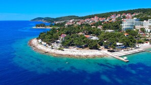 An aerial view of a coastal town with a mix of residential buildings, a pier, and clear blue waters. - Beach Residences Caroline (Hvar)