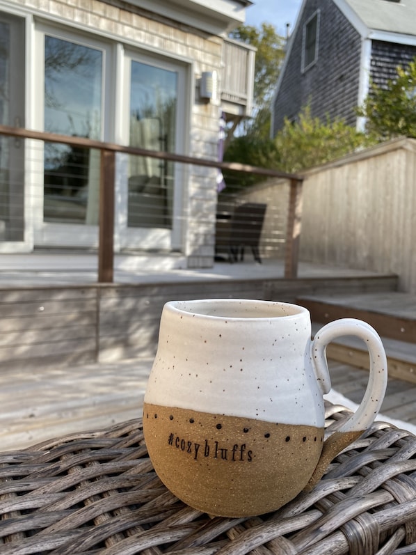A white ceramic mug with a handle on a woven surface. - #CozyBluffs #OakBluffs #EastChop 1 BD, 1.5 bath home-Walk to Town-Ferries-Beach! (Oak Bluffs)