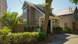 Ein Wohnhaus mit Satteldach, einer Veranda und einem gepflegten Garten mit verschiedenen Pflanzen und Sträuchern.