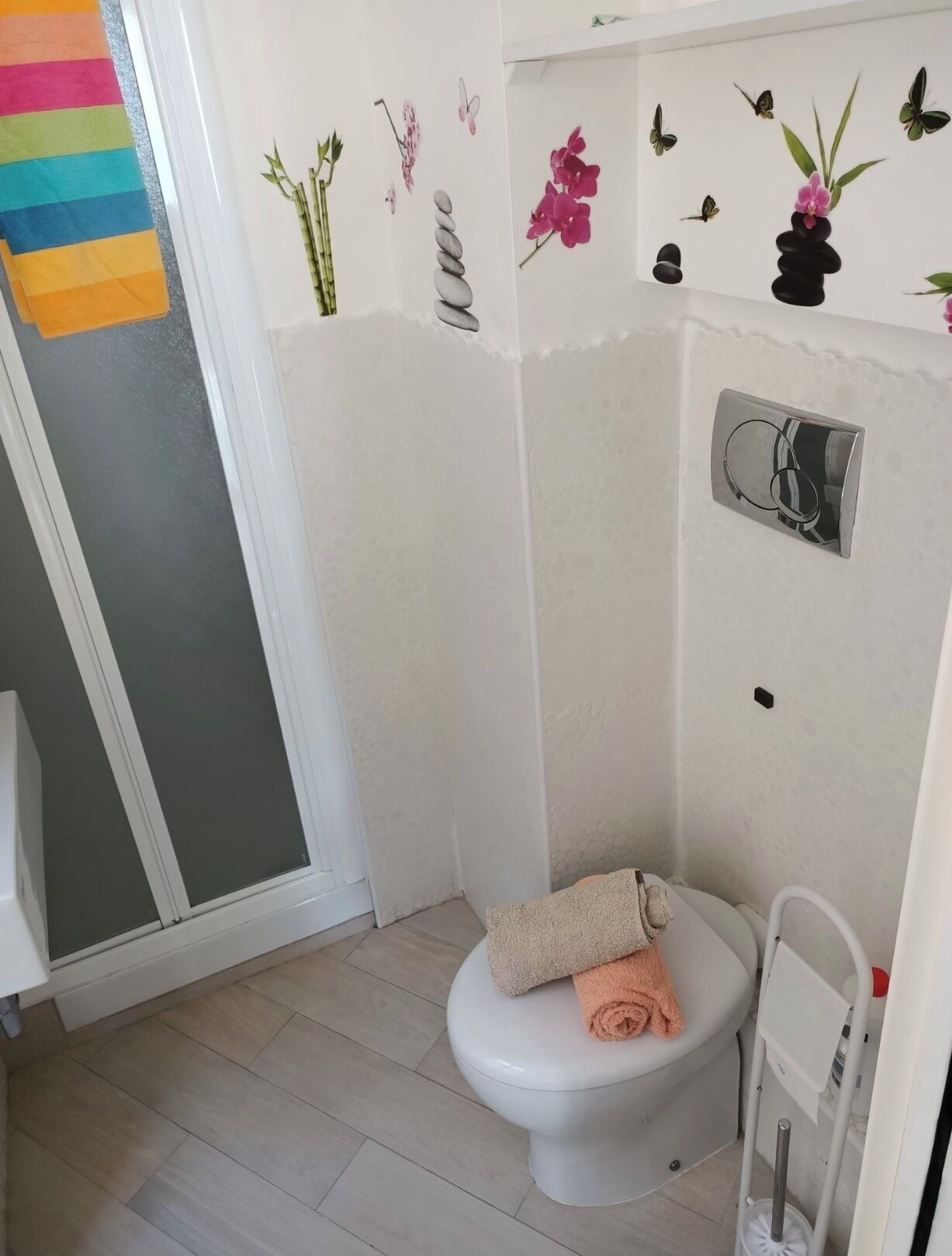 A bathroom with a toilet, a towel, a shower curtain, and decorative wall stickers.