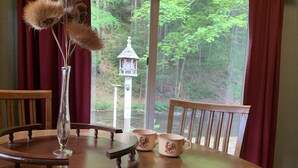 Une table en bois, un vase en verre, deux tasses en céramique et une chaise en bois.