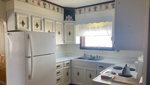 A compact kitchen with white cabinets, a refrigerator, a sink, and a stove.