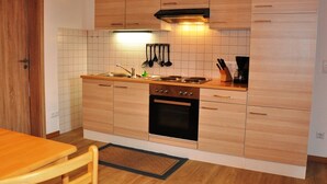 Una cocina compacta con armarios de madera, un horno negro y un salpicadero de azulejos.