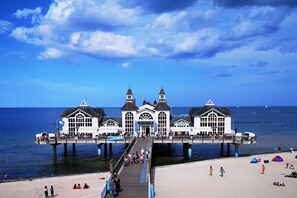 A pier with a white building featuring multiple windows and a central tower, extending into the water.