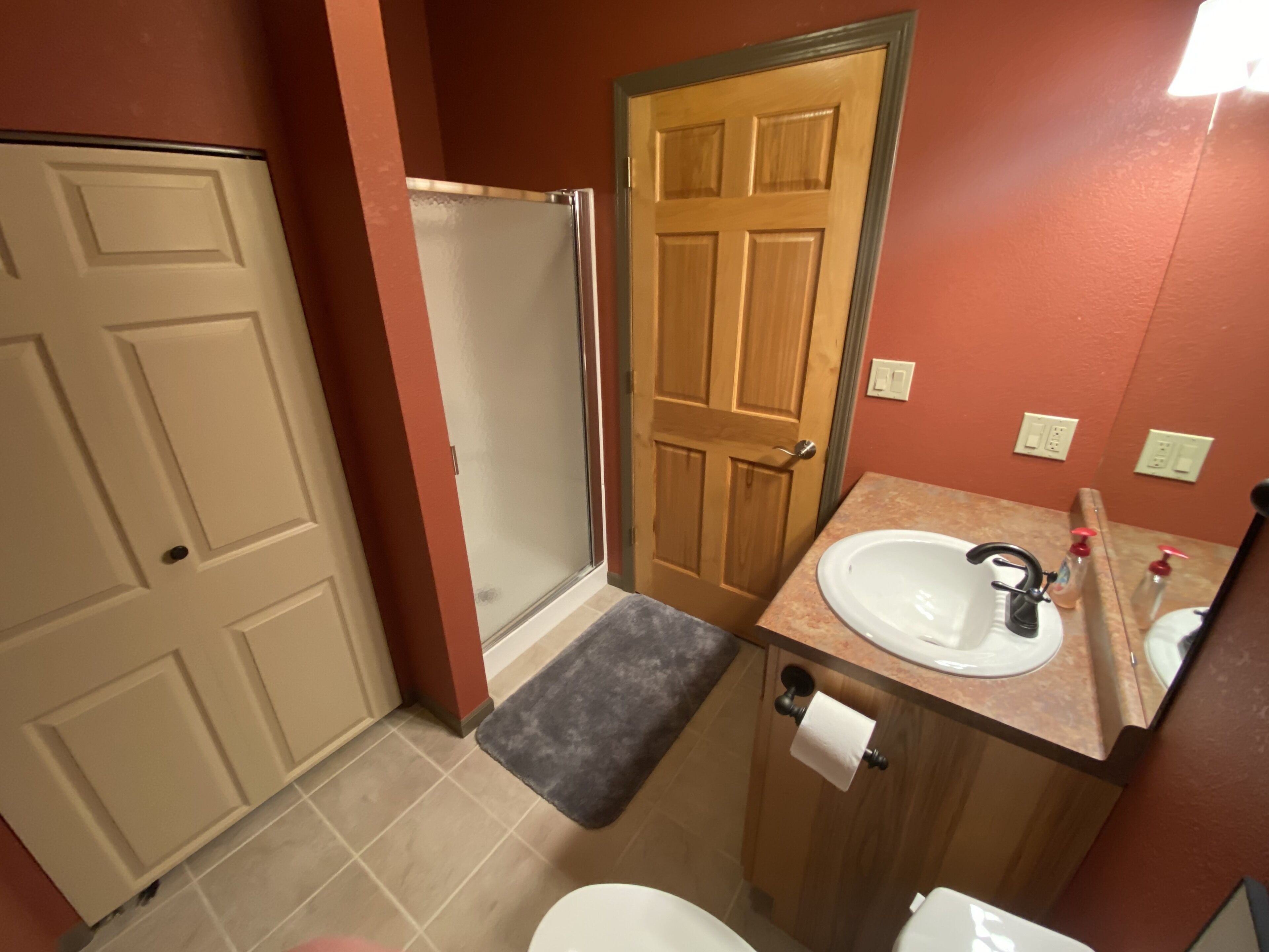 Une salle de bain avec une douche, des toilettes, un lavabo et une porte.