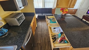 A compact kitchen with a microwave, toaster, and wooden drawers containing kitchen utensils. - Key Lime Resorts - Unit #3 Key Lime Cottage (Monticello)