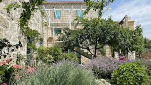 Un edificio in pietra con un giardino antistante, ricco di piante e fiori.
