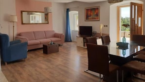 Un soggiorno con divano, televisore, tavolo da pranzo, sedie e un quadro.