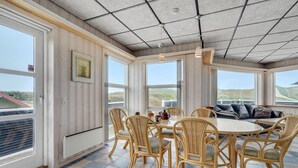 Ein Essbereich mit Tisch und Stühlen, große Fenster mit Landschaftsblick und eine Decke mit Gittermuster.