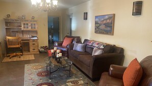 Ein Wohnzimmer mit einem braunen Ledersofa, einem Holztisch und einer Kronleuchter.