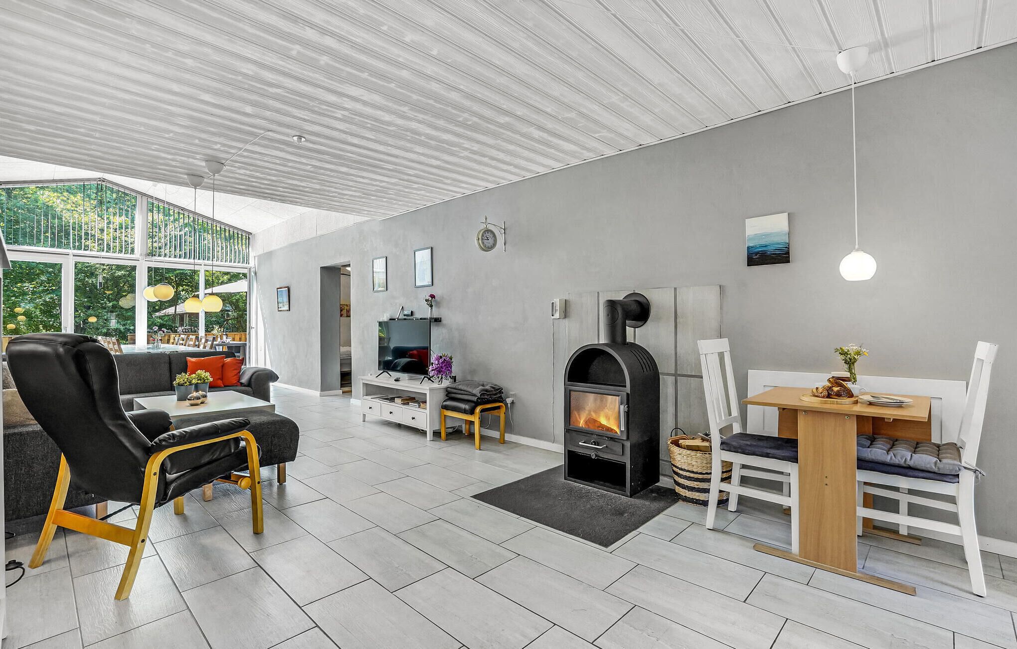 Una sala de estar moderna con chimenea, comedor y zona de estar con sofá y sillones.
