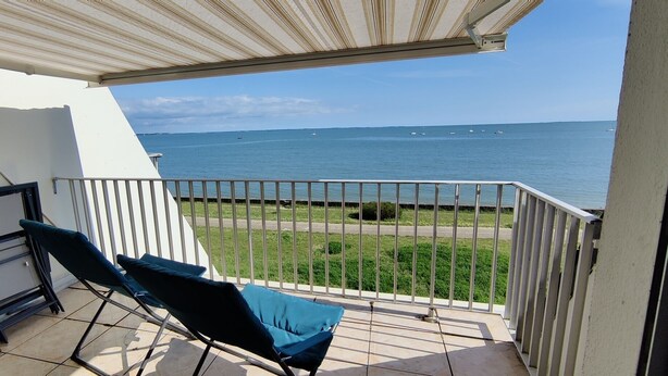 A balcony with two blue lounge chairs, a white awning, and a view of the sea with boats. - Magnificent sea view, direct access to the beach. 4-person apartment (Damgan)