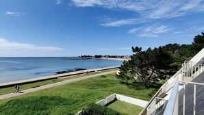 A coastal view with a clear sky, a pathway leading to the beach, and a building with a sloped roof. - Magnificent sea view, direct access to the beach. 4-person apartment (Damgan)